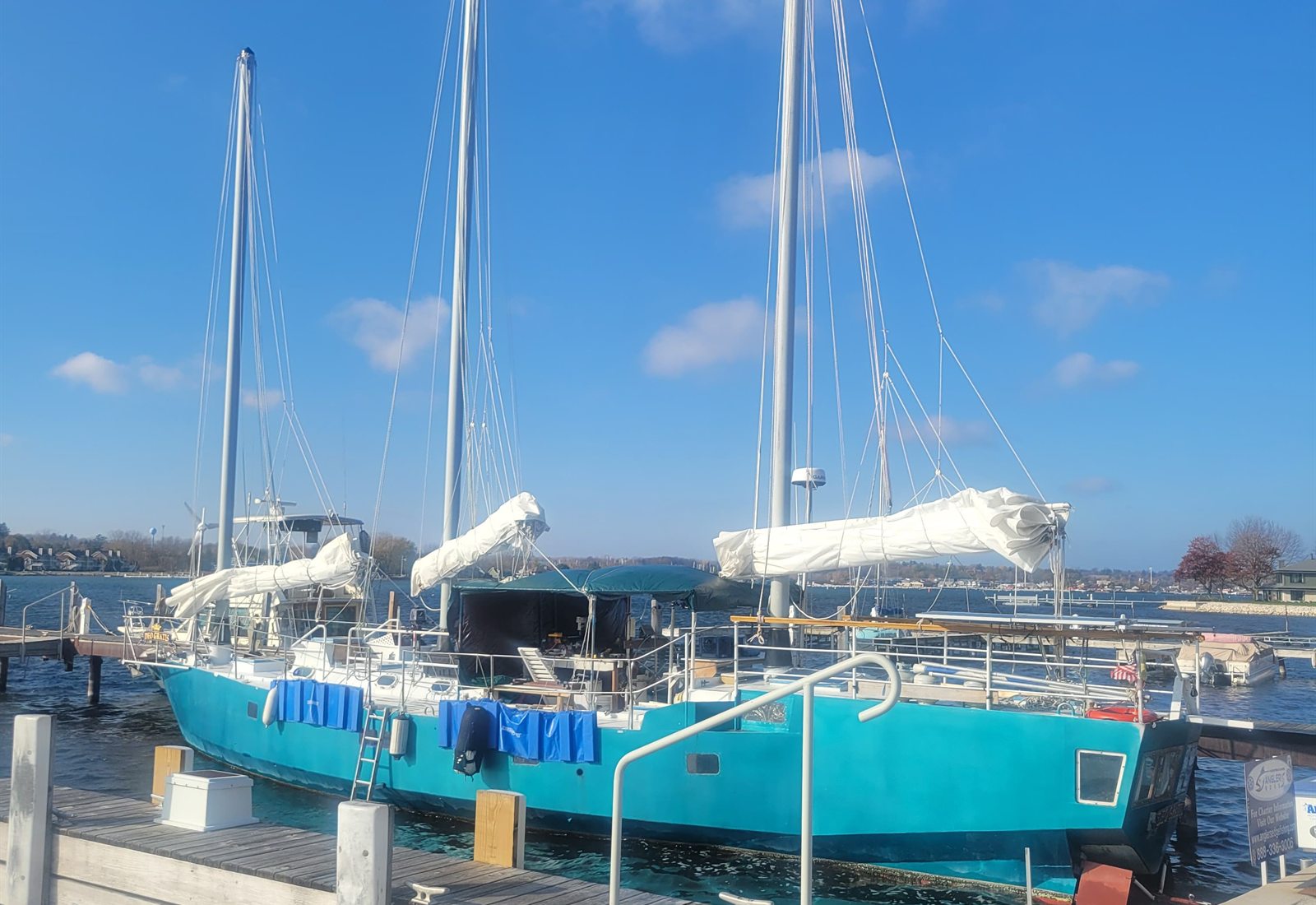 The three masts of Deo Gratis against a clear blue sky